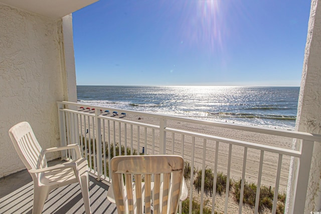 balcony with a water view and a view of the beach