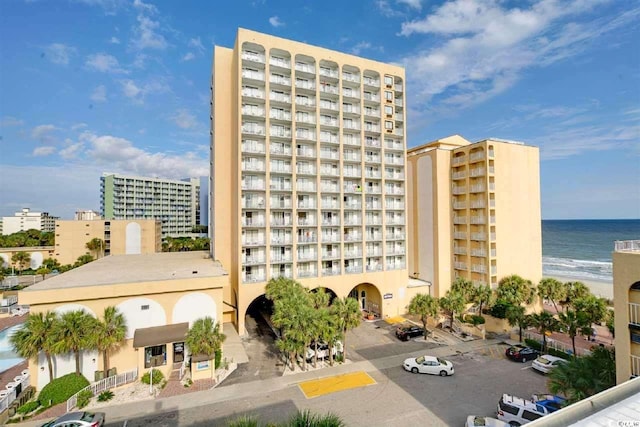 view of property with uncovered parking, a city view, and a water view