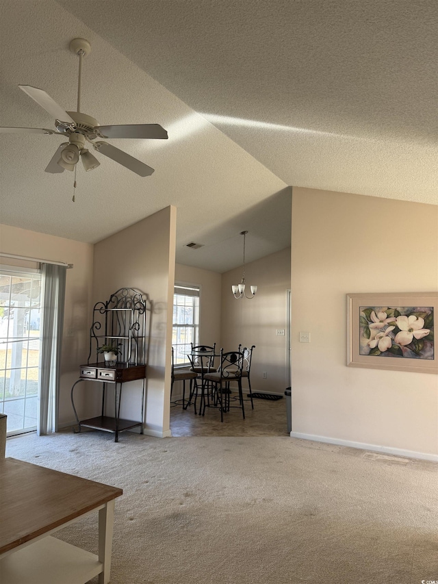 carpeted dining room with lofted ceiling, a textured ceiling, ceiling fan with notable chandelier, and baseboards