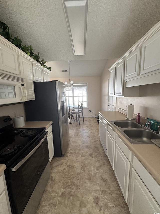 kitchen featuring electric stove, white microwave, a sink, and white cabinets