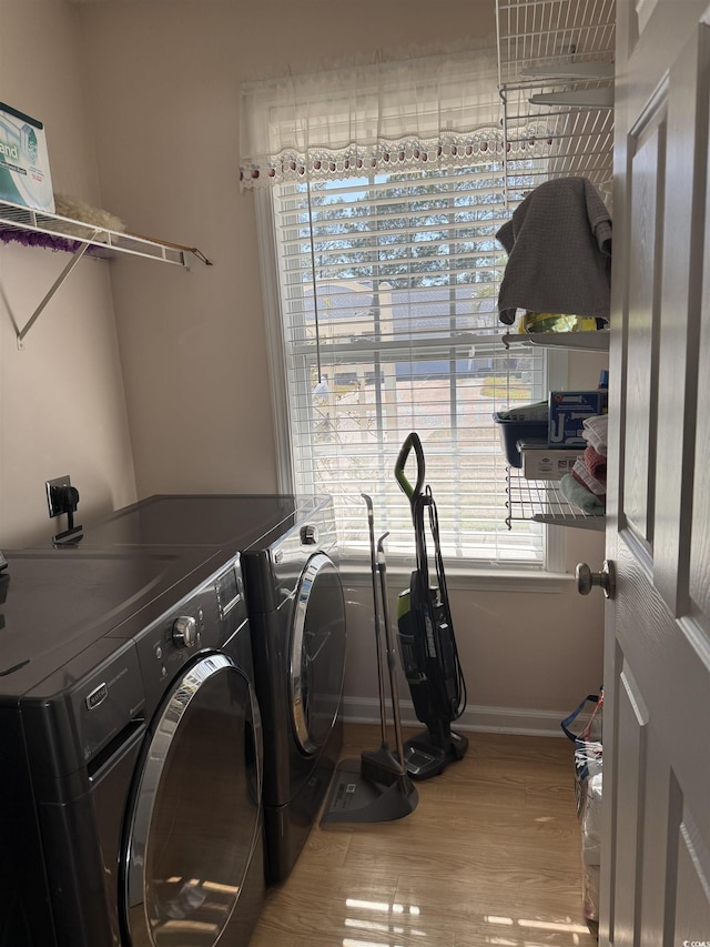 clothes washing area with laundry area, baseboards, wood finished floors, and independent washer and dryer