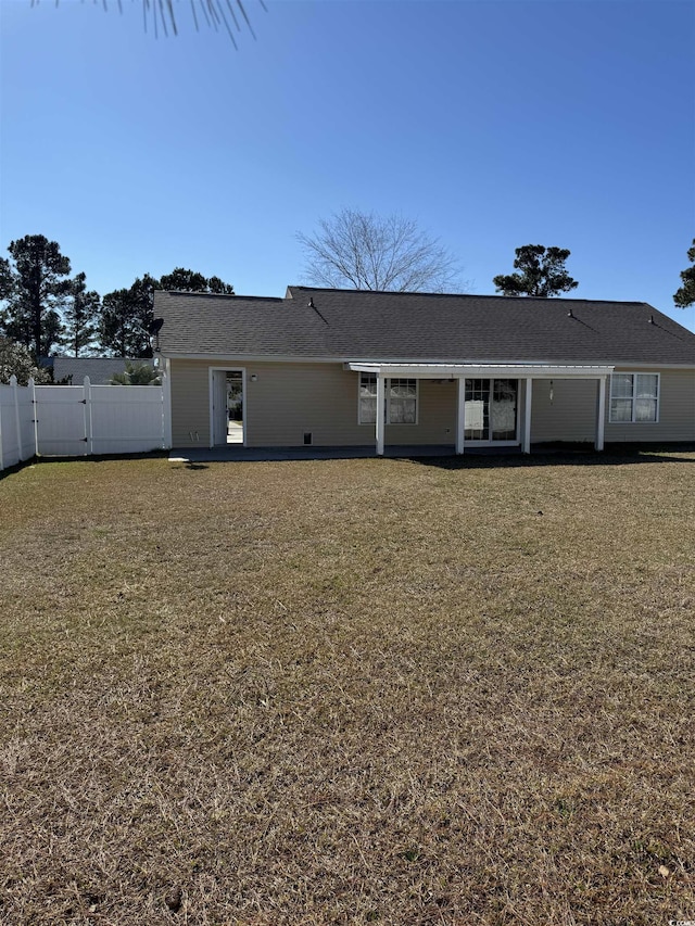 rear view of property with a lawn, fence, and a gate