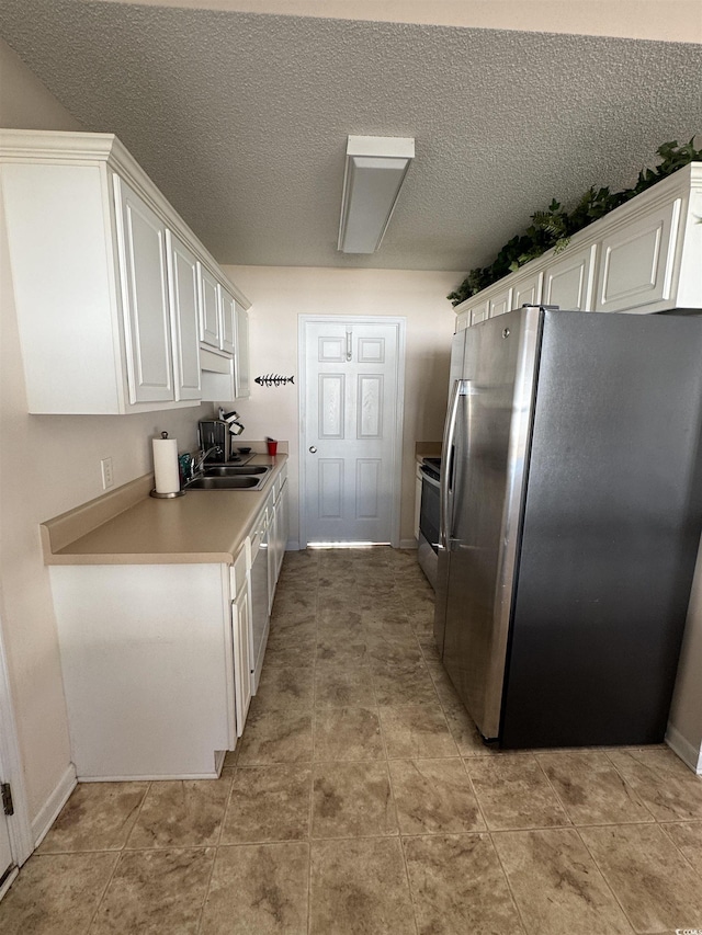 kitchen with white cabinets, stainless steel fridge, a sink, and range with electric stovetop