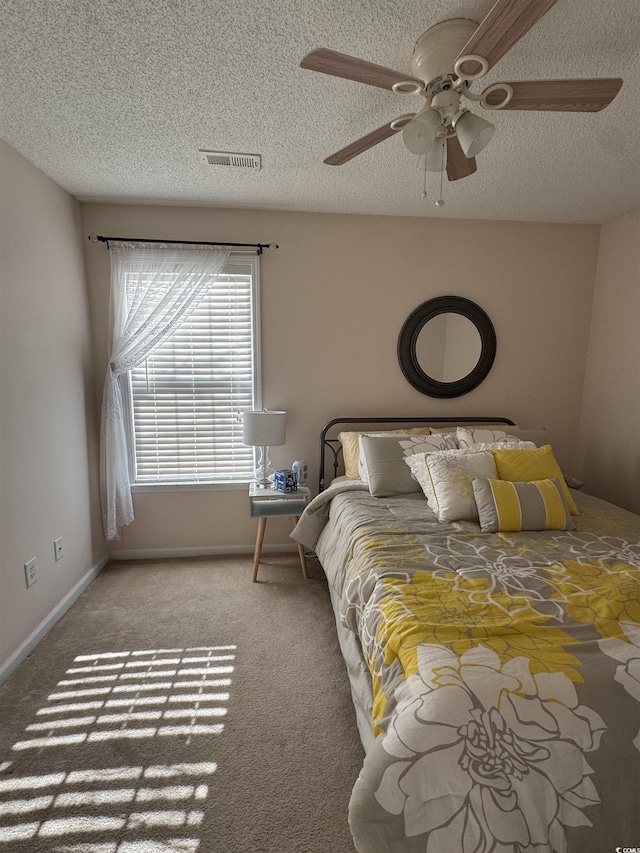 unfurnished bedroom featuring a textured ceiling, visible vents, baseboards, a ceiling fan, and carpet