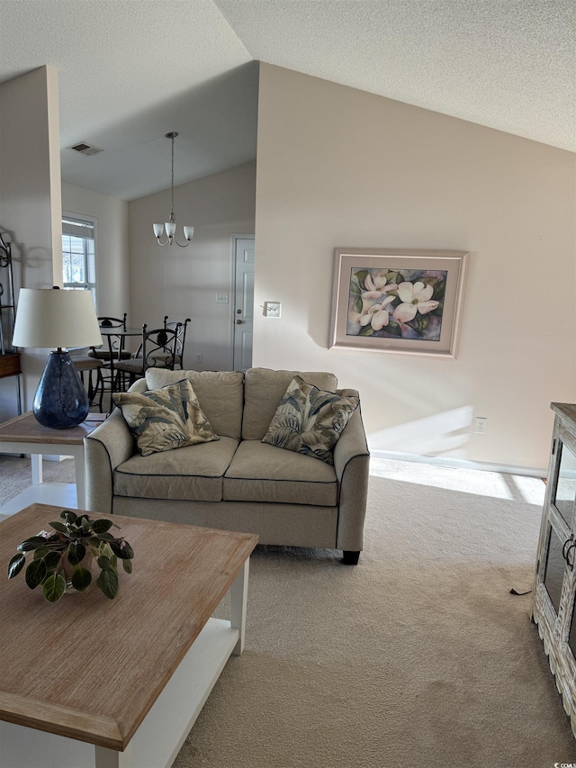 living area with visible vents, an inviting chandelier, vaulted ceiling, a textured ceiling, and carpet floors