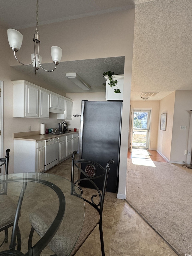 kitchen with freestanding refrigerator, white cabinets, light carpet, a textured ceiling, and dishwasher