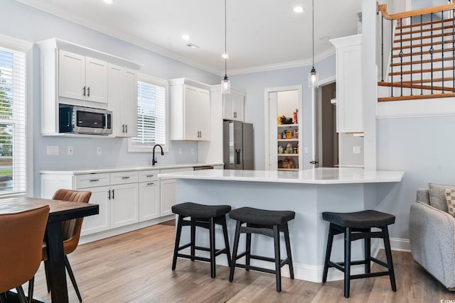 kitchen with stainless steel appliances, a breakfast bar, light countertops, and a sink