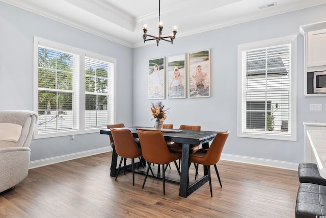 dining space with crown molding, visible vents, wood finished floors, a chandelier, and baseboards