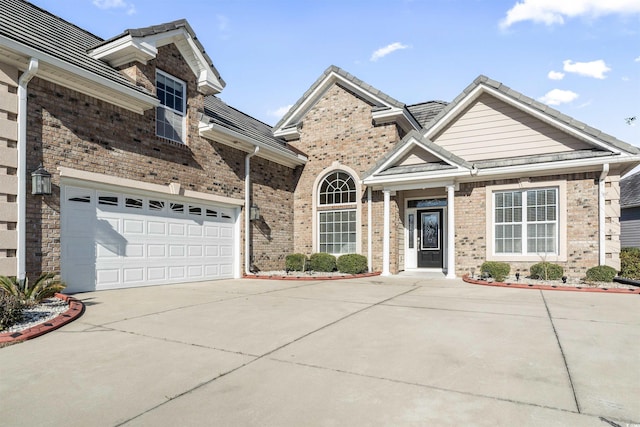 view of front of property with a garage, driveway, a tile roof, and brick siding