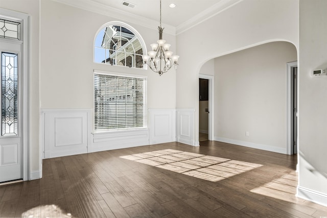 unfurnished dining area with plenty of natural light, arched walkways, and wood finished floors