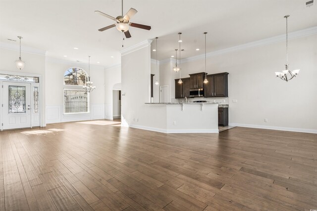 unfurnished living room featuring baseboards, dark wood finished floors, ornamental molding, ceiling fan with notable chandelier, and recessed lighting