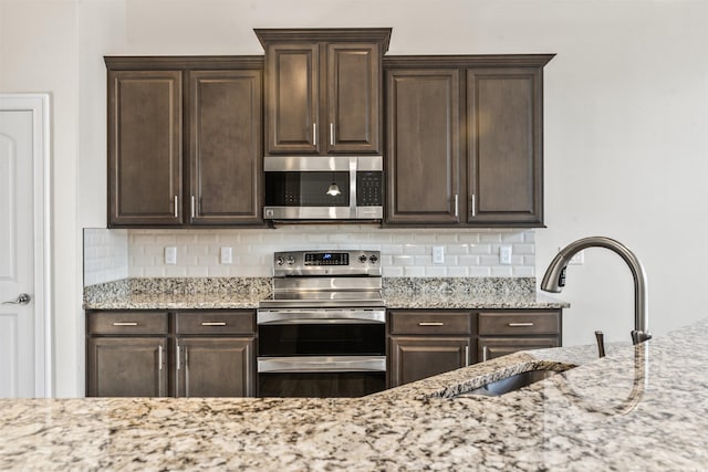 kitchen featuring stainless steel appliances, a sink, decorative backsplash, and dark brown cabinetry