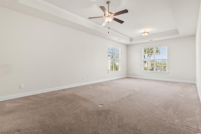 unfurnished room featuring light carpet, baseboards, a raised ceiling, and crown molding