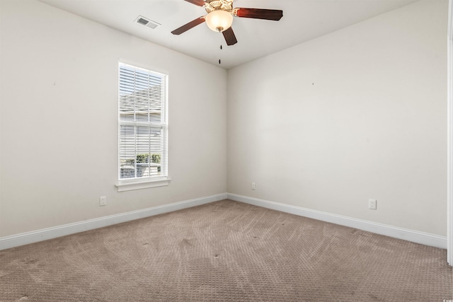 unfurnished room with a ceiling fan, visible vents, light carpet, and baseboards