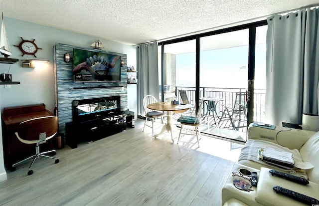 living area with a textured ceiling, a wall of windows, and wood finished floors