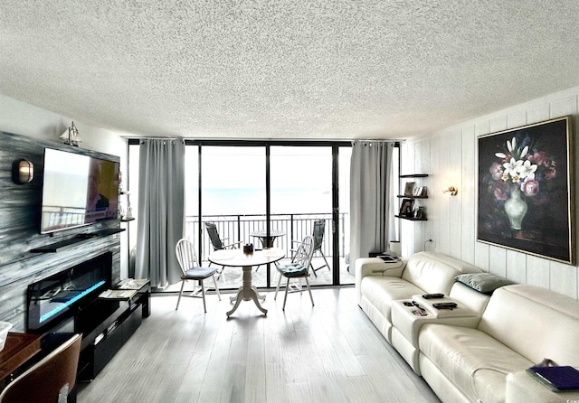 living area with a wall of windows, a textured ceiling, and wood finished floors