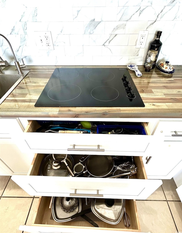 details with black electric stovetop, tasteful backsplash, and a sink