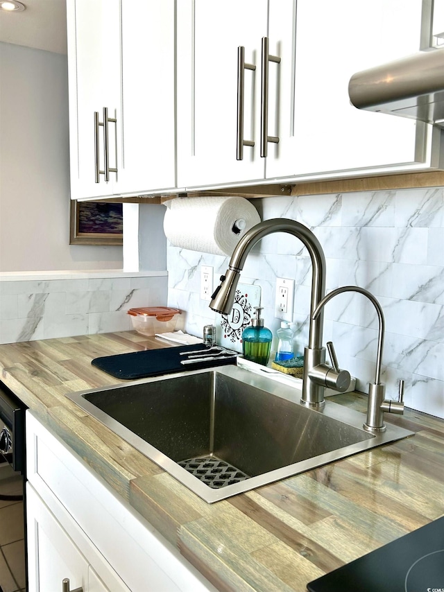 room details with tasteful backsplash, white cabinets, light countertops, and a sink