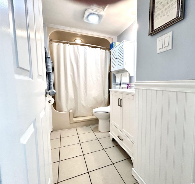 bathroom featuring tile patterned floors, shower / tub combo, toilet, and a wainscoted wall