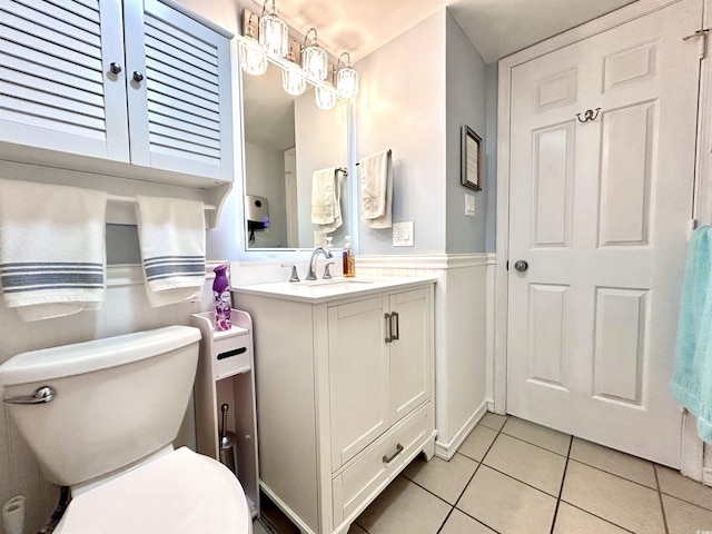 bathroom with tile patterned floors, toilet, wainscoting, and vanity