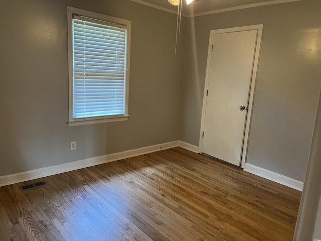 unfurnished room featuring ornamental molding, baseboards, and wood finished floors