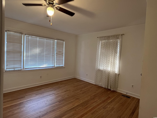 unfurnished room featuring a ceiling fan, visible vents, baseboards, and wood finished floors