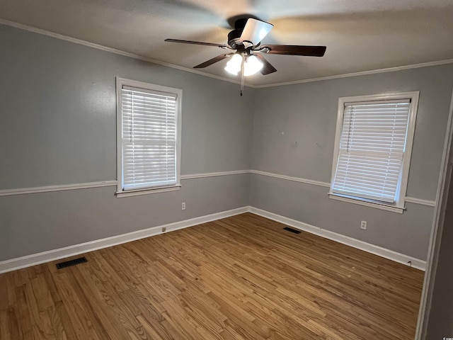 unfurnished room with baseboards, wood finished floors, visible vents, and crown molding