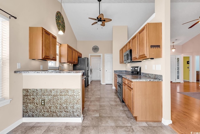 kitchen featuring high vaulted ceiling, stainless steel appliances, a sink, a ceiling fan, and baseboards