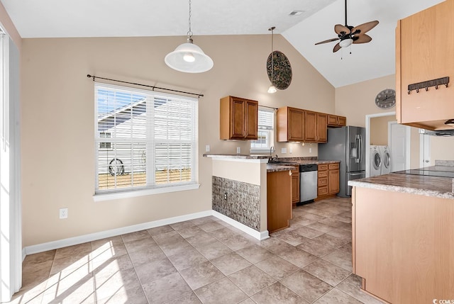 kitchen with brown cabinetry, plenty of natural light, stainless steel appliances, and washer and dryer