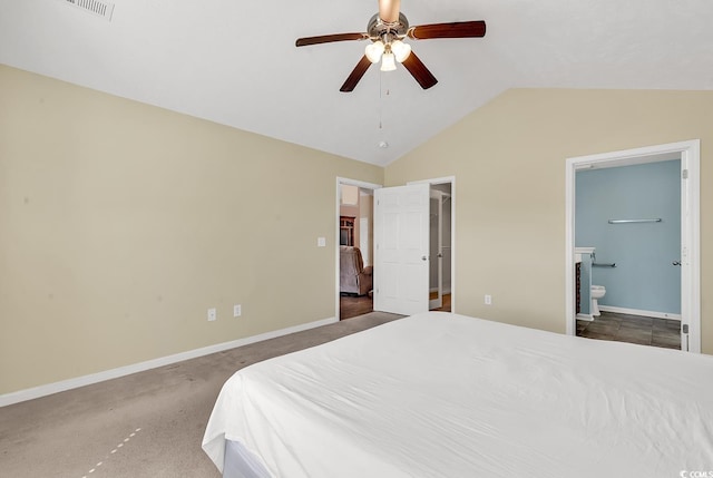 carpeted bedroom with ceiling fan, vaulted ceiling, baseboards, and ensuite bathroom