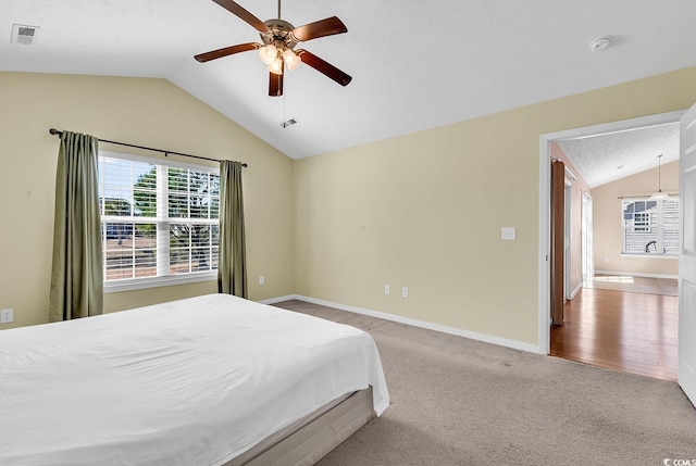 carpeted bedroom with lofted ceiling, baseboards, visible vents, and a ceiling fan