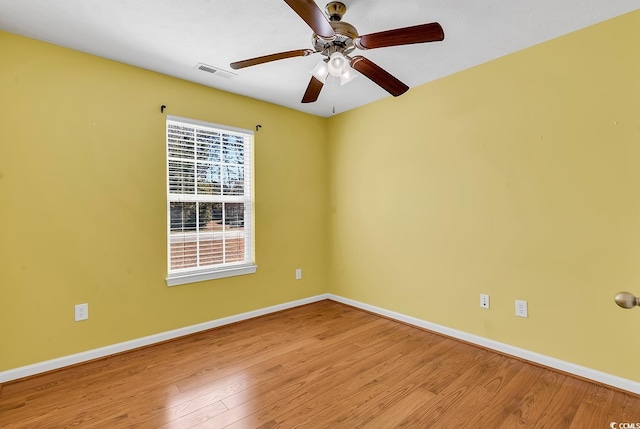 empty room with a ceiling fan, baseboards, visible vents, and wood finished floors