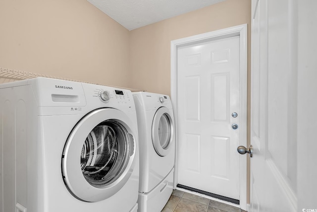 laundry room with laundry area, light tile patterned flooring, a textured ceiling, and washing machine and clothes dryer