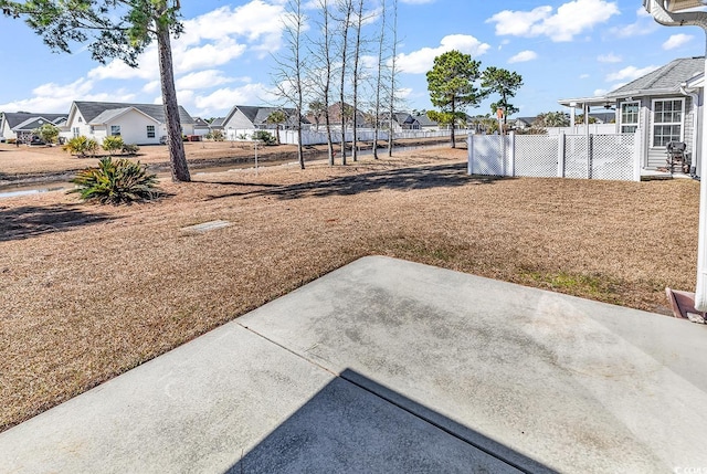 view of yard featuring a residential view, fence, and a patio