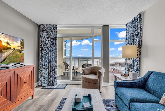 living area with expansive windows, a textured ceiling, baseboards, and wood finished floors