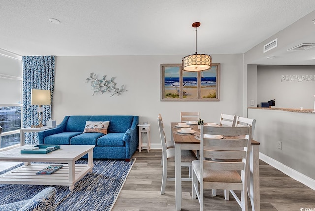 dining room with a textured ceiling, visible vents, and wood finished floors