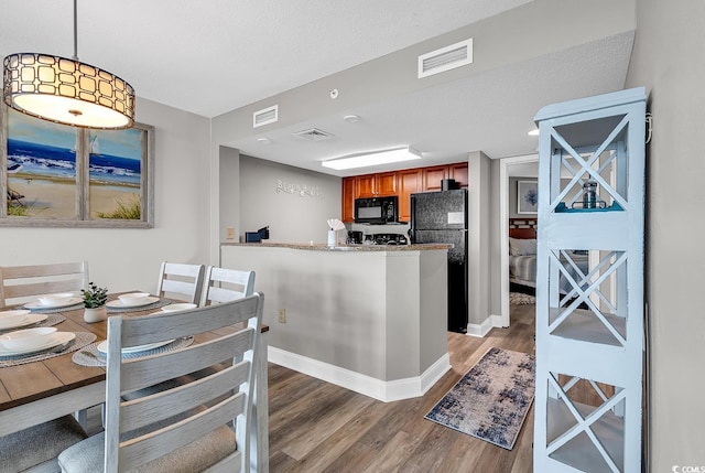 kitchen featuring light wood-type flooring, black appliances, visible vents, and brown cabinets