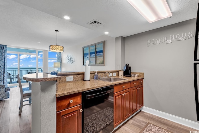 kitchen featuring light wood finished floors, visible vents, dishwasher, a peninsula, and a sink