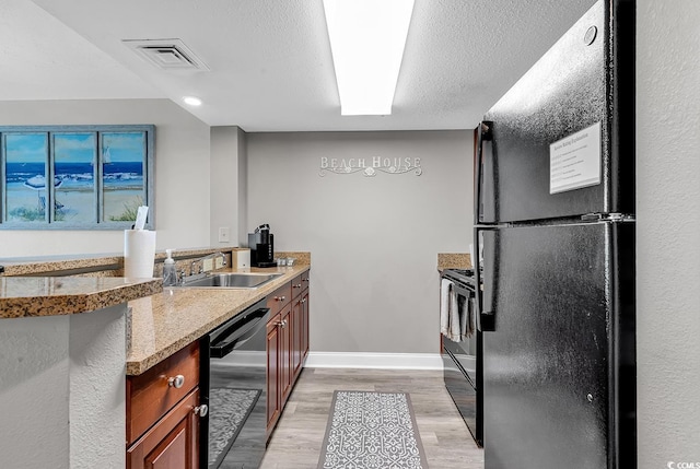 kitchen featuring a peninsula, visible vents, light wood-type flooring, light stone countertops, and black appliances