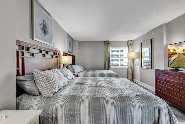 bedroom with a textured ceiling, wood finished floors, and baseboards