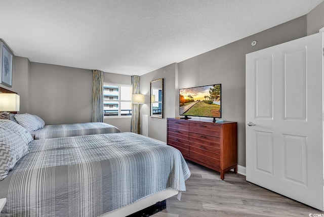 bedroom featuring a textured ceiling, baseboards, and wood finished floors