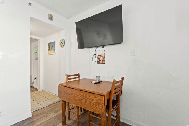 dining space with crown molding, baseboards, and wood finished floors