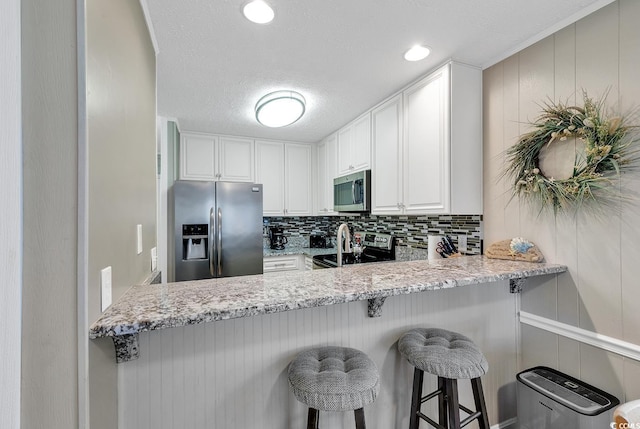 9501 Shore Dr Unit D-132, Myrtle Beach, SC 29572 - kitchen featuring appliances with stainless steel finishes, white cabinets, decorative backsplash, and light stone countertops