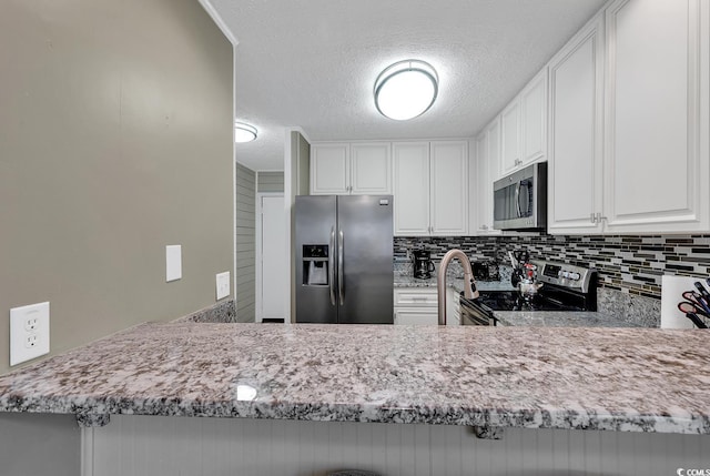 9501 Shore Dr Unit D-132, Myrtle Beach, SC 29572 - kitchen with a textured ceiling, stainless steel appliances, light stone counters, and backsplash