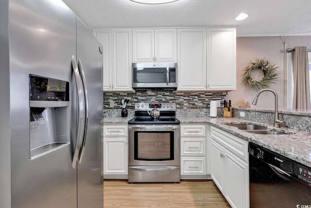 9501 Shore Dr Unit D-132, Myrtle Beach, SC 29572 - kitchen with stainless steel appliances, decorative backsplash, white cabinets, a sink, and light wood-type flooring