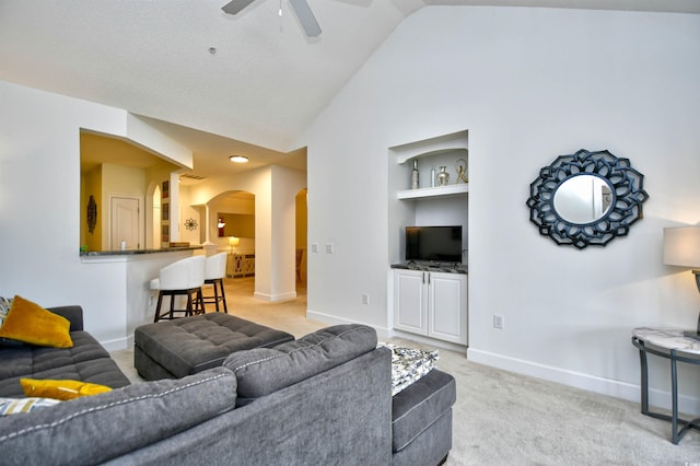 living room featuring light carpet, a ceiling fan, built in features, arched walkways, and baseboards