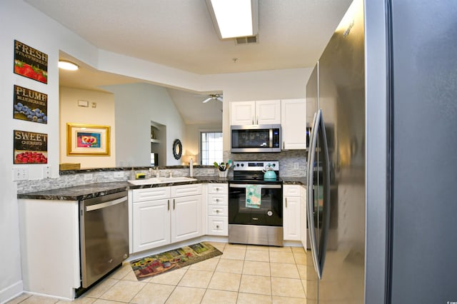 kitchen featuring light tile patterned floors, backsplash, white cabinetry, and stainless steel appliances