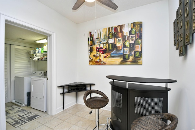 dining area featuring ceiling fan, washing machine and dryer, light tile patterned floors, baseboards, and a dry bar