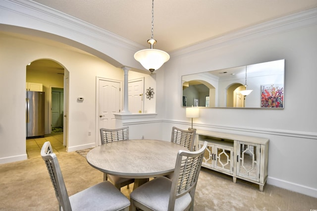 dining room with crown molding, baseboards, arched walkways, and light carpet