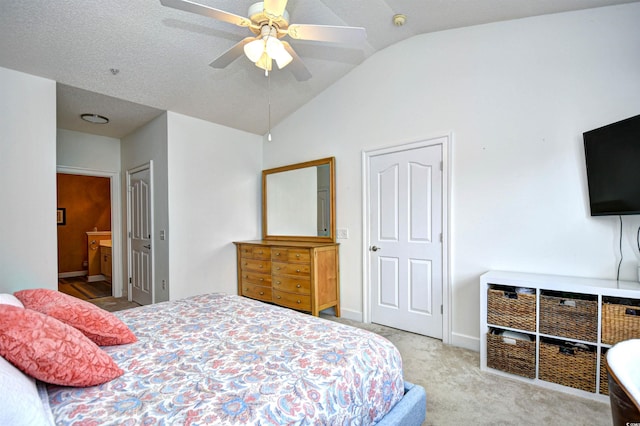 bedroom with baseboards, ceiling fan, lofted ceiling, carpet floors, and ensuite bath